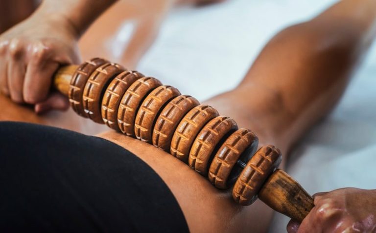 Un massage des jambes avec un rouleau en bois pour détendre les muscles.